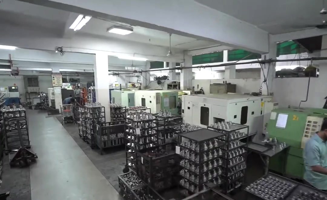 An operator at a CNC lathe with the machine line behind
